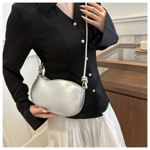 Detail of silver crescent crossbody bag with metallic finish and knotted strap design