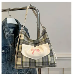 Detail of grey-green plaid tote bag with white flap pocket and pink bow embroidery