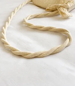 Detail van gedraaide touwschouderband en kanten strik op een geweven strooien tas