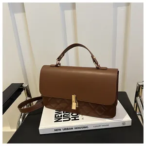 Gros plan d'un sac à main marron matelassé avec une boucle en métal doré élégante