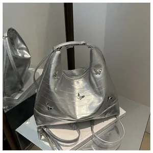 Detail of silver hobo bag featuring 3D metal butterfly on metallic embossed leather