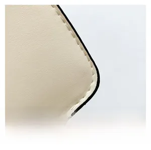 Dettaglio della pelle beige con cuciture bianche precise sulla borsa a tracolla