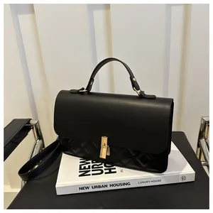 Détail d'un sac à bandoulière matelassé noir avec boucle dorée sur des livres