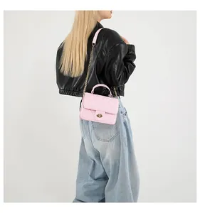 Pink quilted crossbody bag with gold chain strap and metal lock shown on a model
