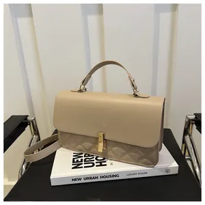 Détail d'un sac matelassé beige doté d'un fermoir pivotant rectangulaire en métal doré