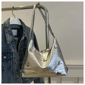 Detail of silver metallic underarm bag with butterfly accents and Y2K aesthetic style