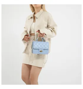 Detail of light blue quilted crossbody bag featuring a golden metal twist lock and chain strap