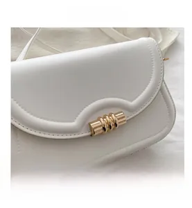 Detail view of smooth white PU leather crossbody bag with wave edge and gold metal buckle