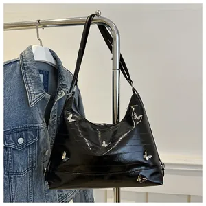 Close-up of black patent leather hobo bag with silver butterfly hardware details