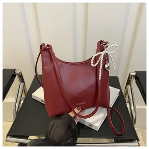 Détail du sac bandoulière bordeaux en similicuir avec texte fashion et breloque perle