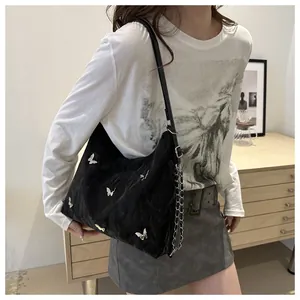 Detail of black pleated shoulder bag with silver butterfly charms and chain strap
