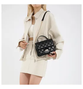 Detail of black quilted crossbody bag featuring golden twist lock and chain strap on model
