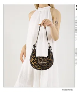 Detail of leopard print crescent bag featuring a gold metal buckle and soft fabric texture