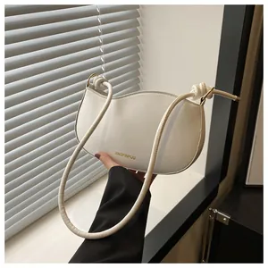 Detail of white crescent shoulder bag with knotted leather straps and golden logo
