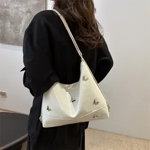 White faux crocodile skin shoulder bag with silver butterfly charms shown on model