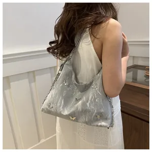 Detail of silver-grey butterfly hobo bag with metallic charms and pleated fabric texture