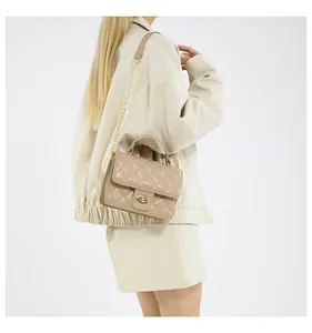 Side view of beige quilted handbag with gold turn-lock and chain strap on female model