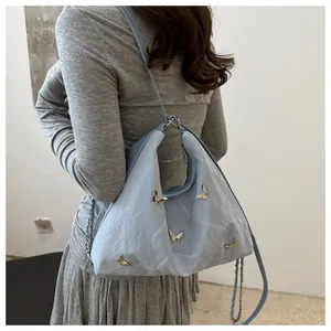Detail view of light blue tote featuring 3D silver butterflies and pleated fabric