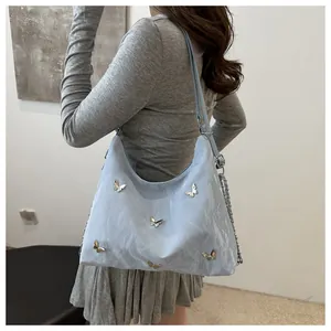Detail of light blue hobo bag with 3D silver butterflies and pleated glossy finish