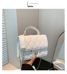 Close-up of white quilted leather crossbody bag with golden chain and metal rotary lock