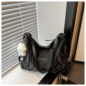 Detail of black pleated tote bag with oval logo plaque and white fluffy cloud charm