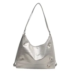 Silver metallic shoulder bag with butterfly hardware and textured surface in 2024 trendy style