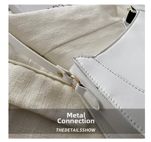 Detail of white leather shoulder bag with gold metal rivets and neat stitching accents