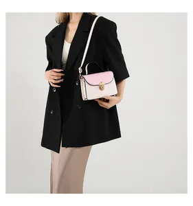 Borsa a tracolla bicolore alla moda con chiusura dorata indossata su un blazer nero