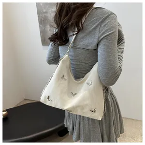 Detail of silver butterfly charms and pleated texture on ivory shoulder bag for women
