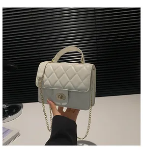 Detail of white quilted crossbody bag with golden chain strap and swivel lock closure