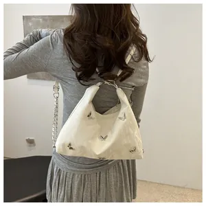 Detailed view of a white ruched tote bag with silver butterfly accents and chain strap