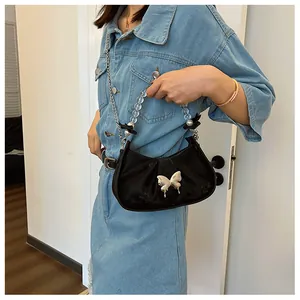 Gros plan sur sac noir avec détail papillon argenté et poignée de perles chic