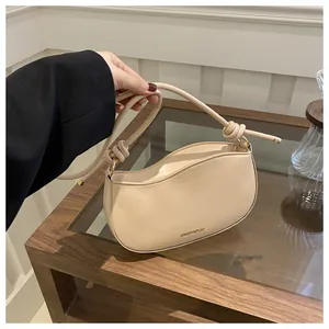 Detail of cream crossbody bag featuring a wavy top edge and stylish knotted leather strap