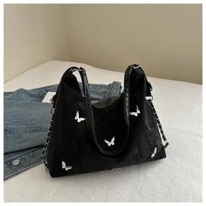 Detail of black tote bag featuring silver butterfly buckles and nylon pleated texture