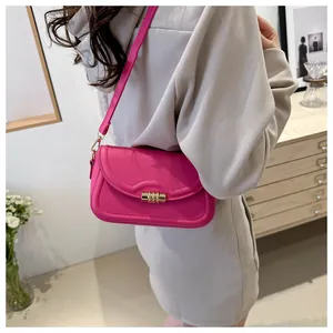 Close-up of pink crossbody bag showing the golden cylindrical twist lock and fine stitching