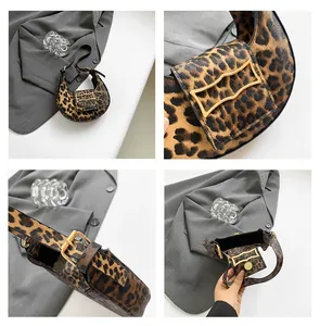 Detailed view of leopard print crescent bag with wavy gold buckle and adjustable strap
