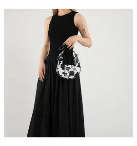 Close-up of stylish cow print crescent shoulder bag with metallic buckle on black dress