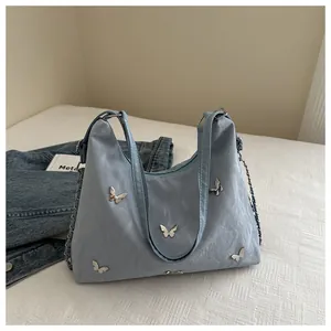 Detail of light blue hobo bag with silver butterfly charms and metal chain strap