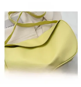 Detail view of lime yellow crossbody bag featuring pebble leather texture and crescent shape