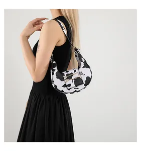 Side view of cow print hobo bag featuring gold metal buckle and wide shoulder strap