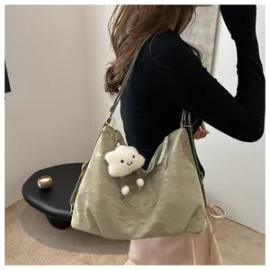 Detail of avocado green pleated tote bag with plush cloud charm and logo embossing