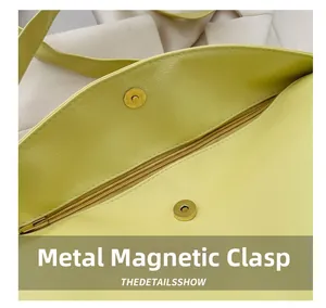 Detail of yellow pebbled leather bag featuring a gold magnetic buckle and metal zipper