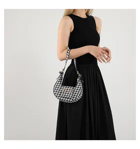 Close-up of houndstooth hobo bag with a metal buckle worn with a black dress