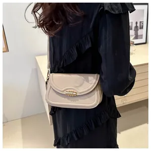 Detail of beige leather crossbody bag featuring a unique gold cylindrical twist lock buckle