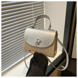 Detail der gewebten Strohhandtasche mit silberner Klappe und goldenem Glockenverschluss