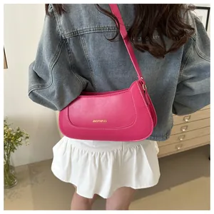 Rear view of a model wearing a hot pink leather shoulder bag with gold lettering