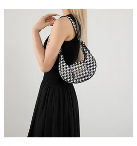 Detailed shot of houndstooth crescent bag with wavy gold metal buckle on flap