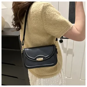 Detail of elegant black crossbody bag featuring a gold metallic cylinder twist lock closure