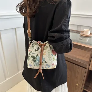 Detailed close-up of a floral jacquard bucket bag with brown leather drawstring and strap