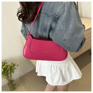 Detail view of the rose red PU leather shoulder bag with gold logo and slim strap